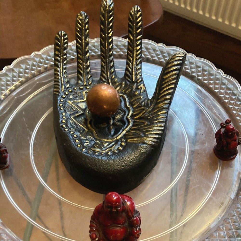 A brass hand cradling a copper sphere, a small altar piece in Camilla's Reiki studio