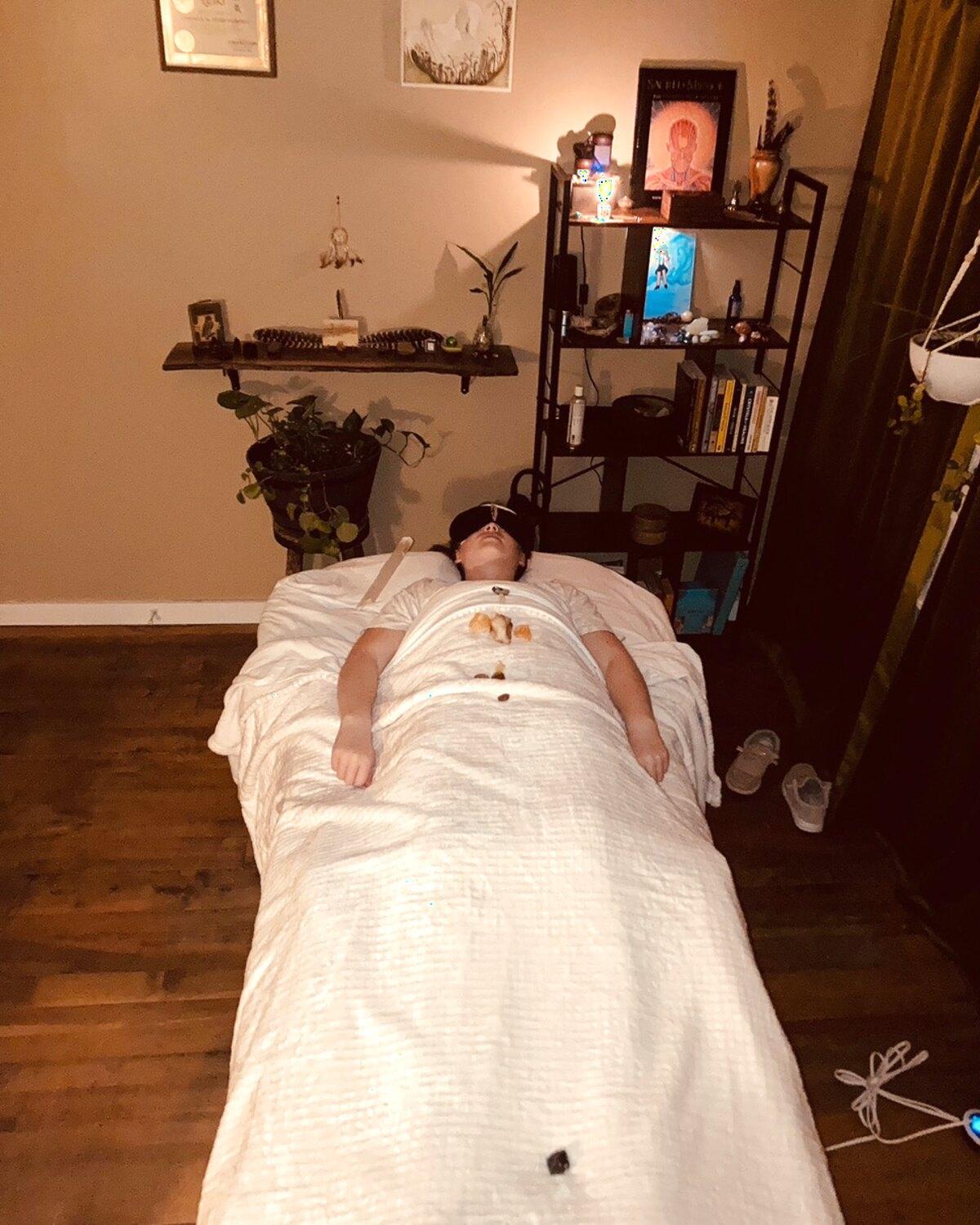 A client resting on the heated table in Camilla's candlelit Reiki studio